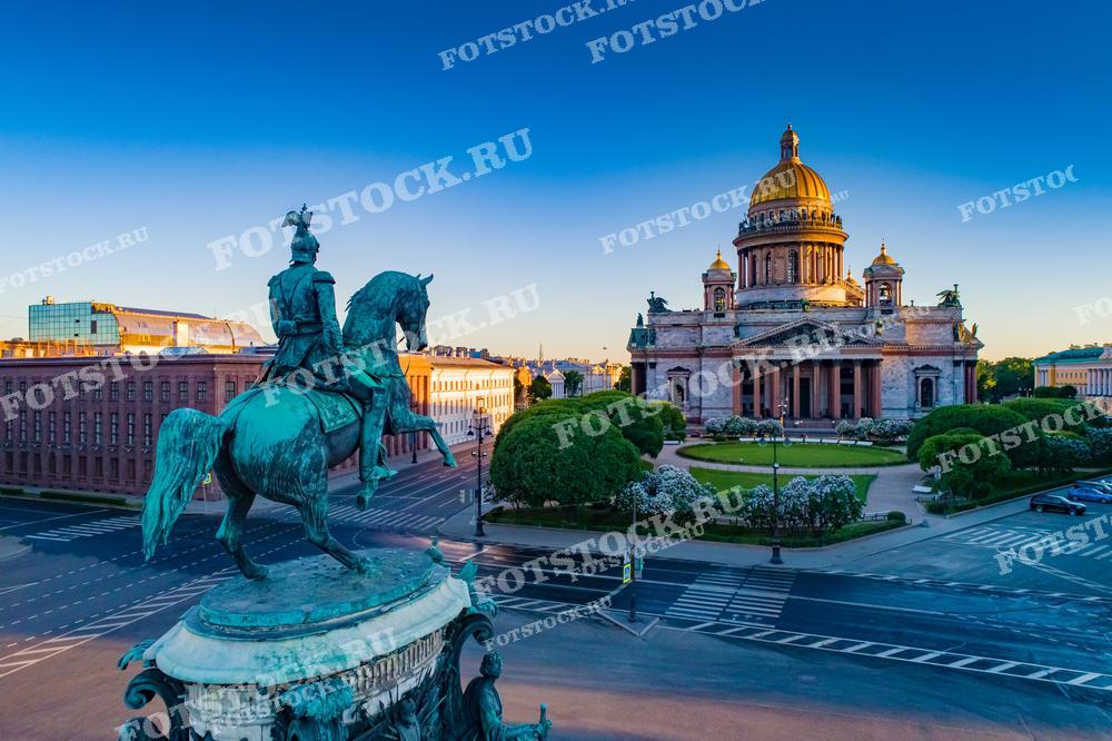 На этой фотографии мы видим Исаакиевский собор в Санкт-Петербурге. В переднем плане расположен памятник на коне, изображающий историческую фигуру, возвышающуюся над пустынной улицей города. Здание собора подсвечено, его купола и фасады выделяются на фоне ясного неба. Фотография может быть использована в туристических брошюрах, исторических книгах, публикациях о знаменитых монументах, а также как визуальный материал для статей о культуре и архитектуре.